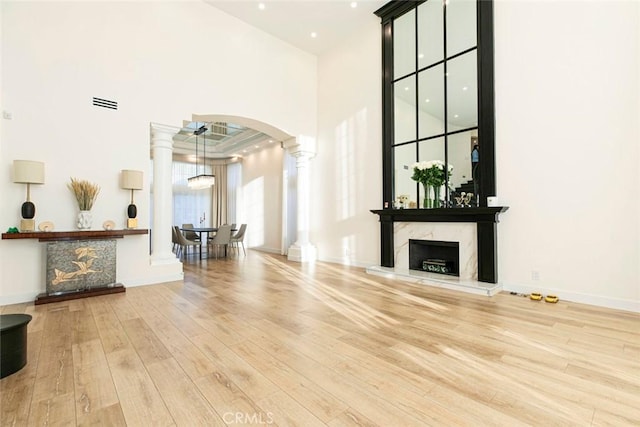 unfurnished living room featuring ceiling fan, a high ceiling, light hardwood / wood-style flooring, and a fireplace