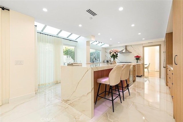 kitchen featuring a breakfast bar, kitchen peninsula, sink, a skylight, and a large island