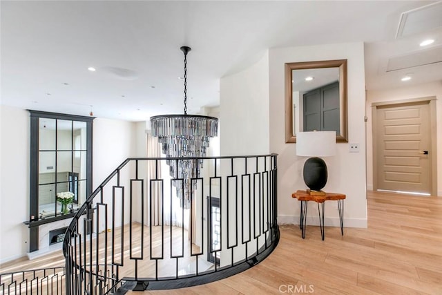 hallway with light wood-type flooring and an inviting chandelier