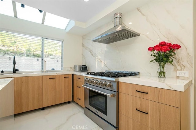 kitchen featuring tasteful backsplash, extractor fan, sink, stainless steel range, and a skylight