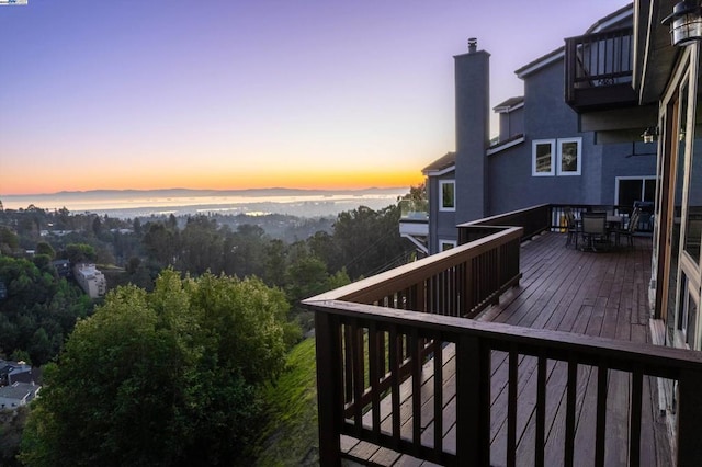 deck at dusk featuring a water view