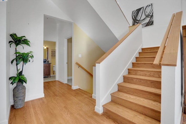 staircase with vaulted ceiling and wood-type flooring