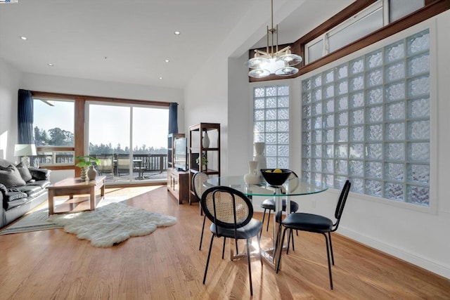 dining area with light wood-type flooring and a notable chandelier