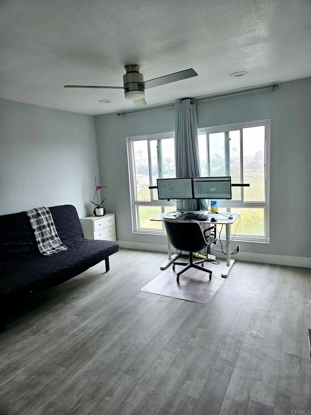 home office with ceiling fan, a textured ceiling, and light hardwood / wood-style flooring