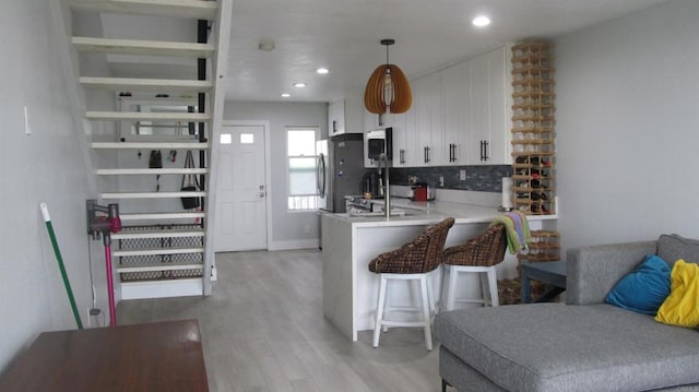 1111 Seacoast Unit 50, Imperial Beach, CA 91932 - kitchen featuring tasteful backsplash, white cabinets, light wood-type flooring, light countertops, and a peninsula
