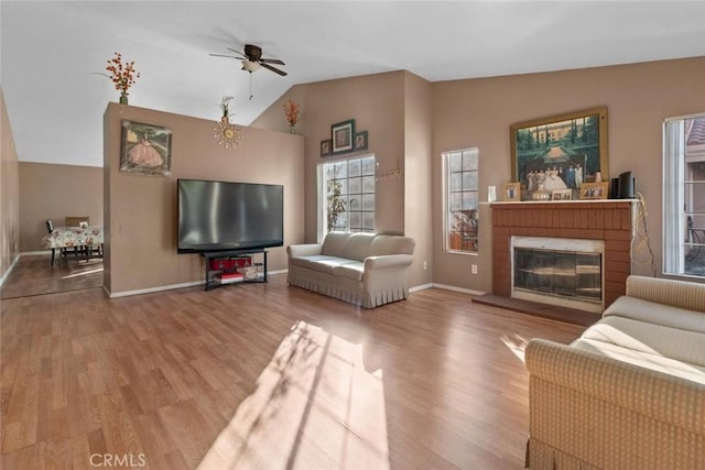 living room with ceiling fan, vaulted ceiling, a brick fireplace, and hardwood / wood-style flooring