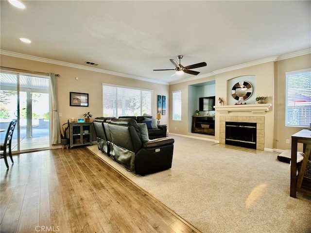 living room with ornamental molding, a healthy amount of sunlight, a fireplace, and light hardwood / wood-style flooring