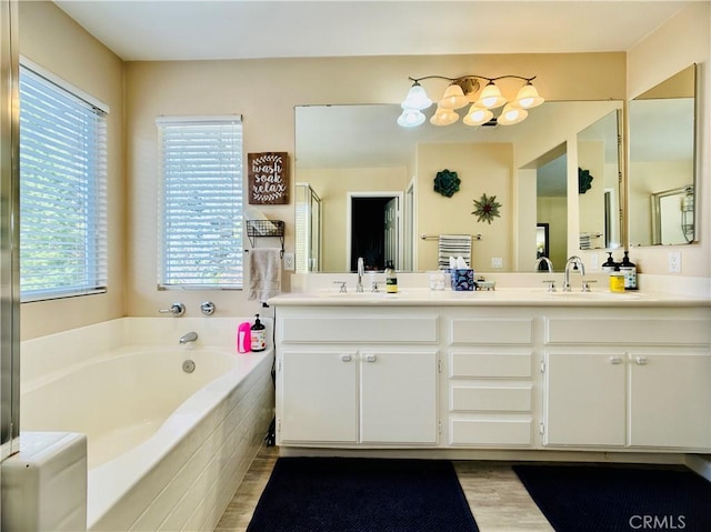 bathroom featuring a healthy amount of sunlight, independent shower and bath, and vanity