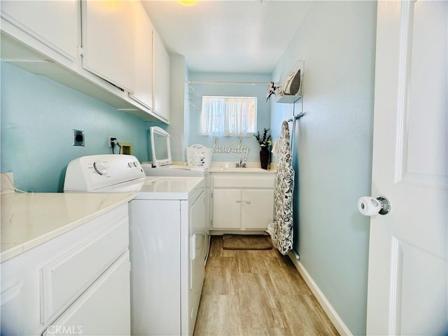 laundry room with independent washer and dryer, sink, cabinets, and light wood-type flooring