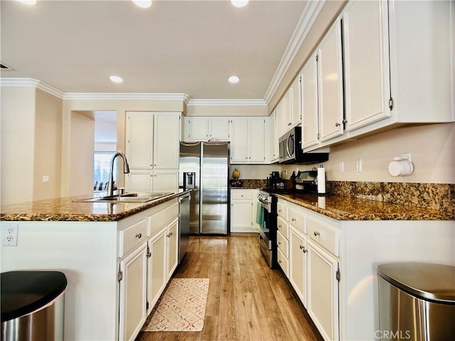 kitchen featuring white cabinetry, sink, dark stone countertops, stainless steel appliances, and light wood-type flooring