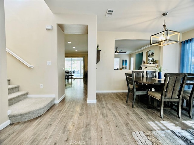 dining space with hardwood / wood-style flooring, crown molding, and ceiling fan with notable chandelier