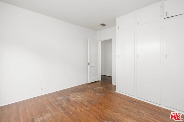 unfurnished bedroom with dark hardwood / wood-style flooring and a closet