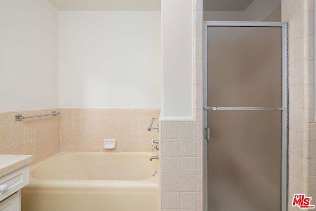 bathroom featuring vanity, tile walls, and a tub