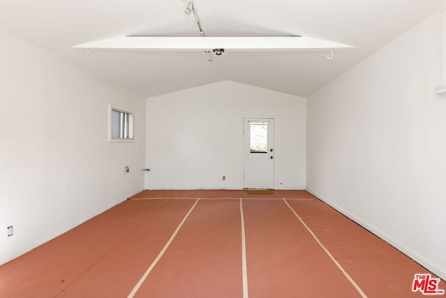 unfurnished room featuring lofted ceiling and rail lighting