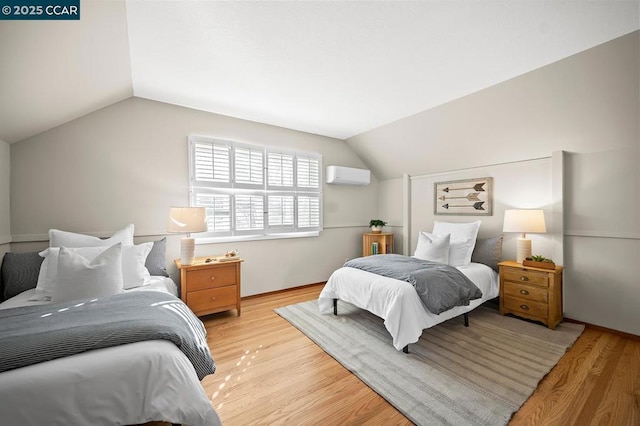 bedroom featuring lofted ceiling, a wall mounted AC, and light hardwood / wood-style flooring