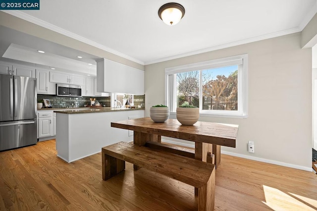 kitchen featuring white cabinetry, stainless steel appliances, tasteful backsplash, light hardwood / wood-style floors, and kitchen peninsula