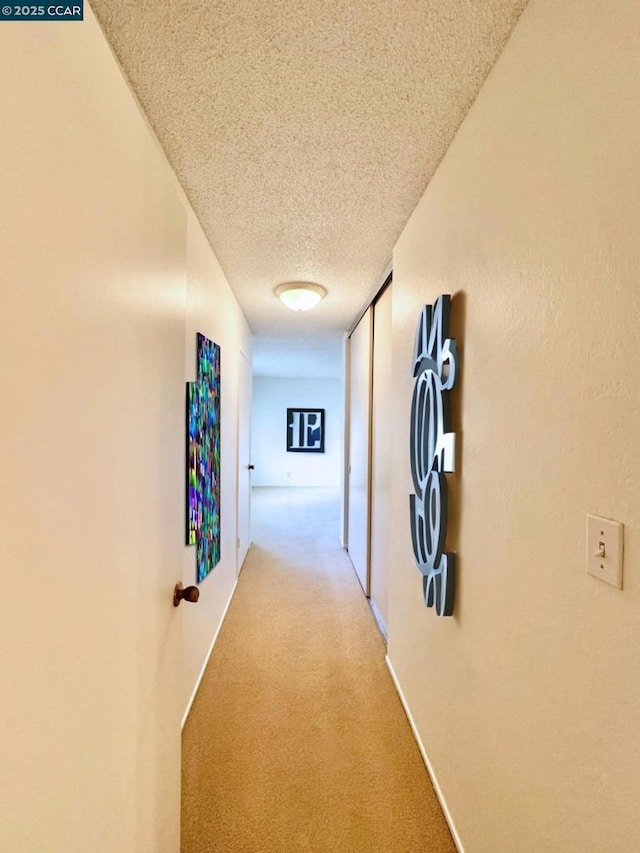 hall with a textured ceiling and light carpet