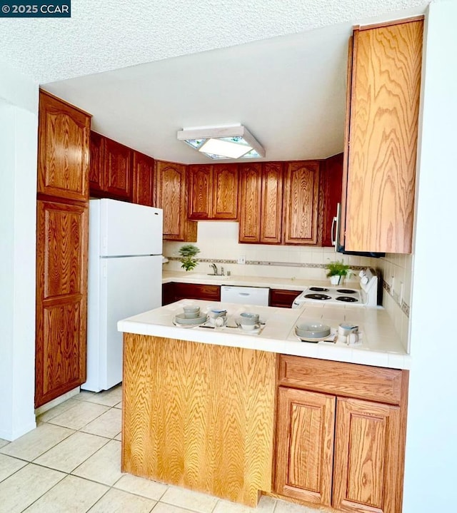 kitchen with light tile patterned floors, decorative backsplash, kitchen peninsula, and white appliances