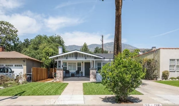 view of front of home featuring a front lawn, a garage, a porch, and a mountain view