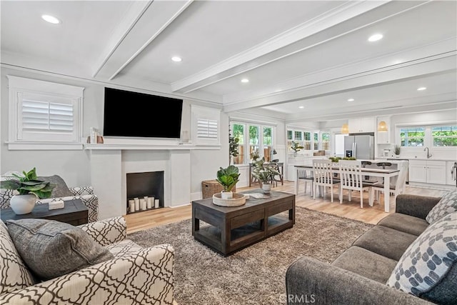 living room with light wood-type flooring, beam ceiling, sink, and crown molding