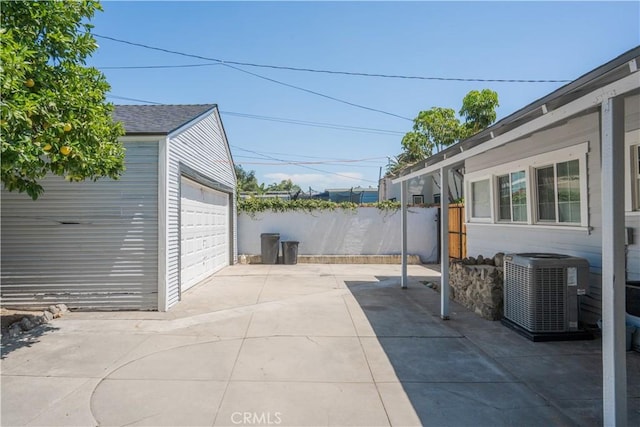 view of patio with a garage, cooling unit, and an outdoor structure