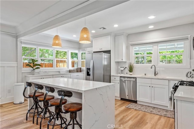 kitchen featuring sink, a kitchen island, white cabinets, and appliances with stainless steel finishes