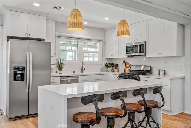 kitchen with white cabinets, hanging light fixtures, and appliances with stainless steel finishes