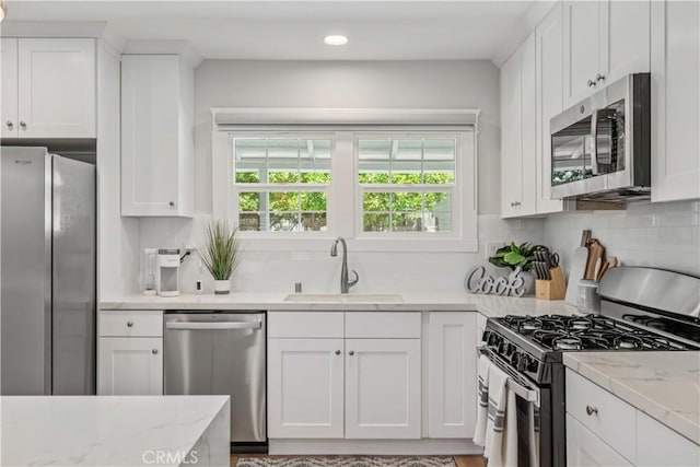 kitchen featuring sink, white cabinetry, light stone countertops, and stainless steel appliances