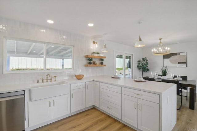 kitchen featuring a wealth of natural light, white cabinetry, stainless steel dishwasher, and kitchen peninsula