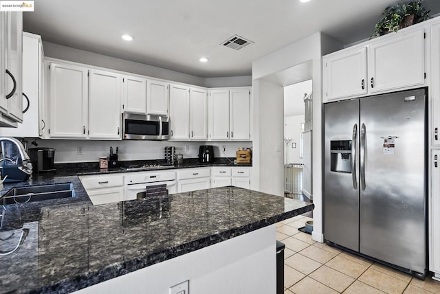 kitchen featuring appliances with stainless steel finishes, light tile patterned floors, sink, white cabinets, and kitchen peninsula