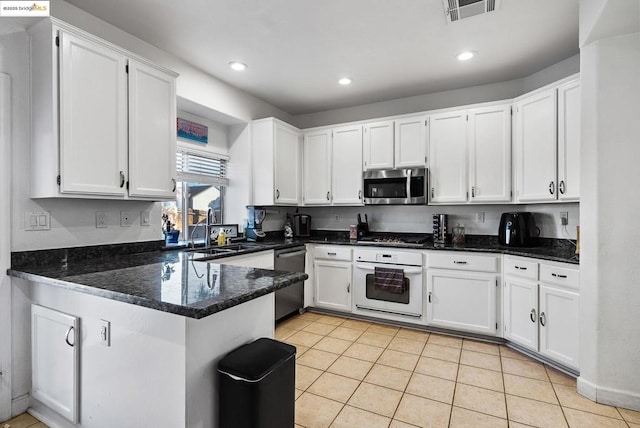 kitchen featuring white cabinets, stainless steel appliances, kitchen peninsula, and light tile patterned floors