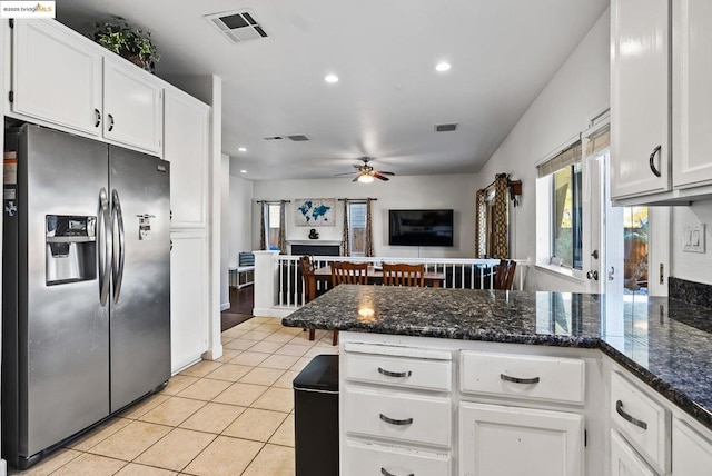 kitchen featuring stainless steel refrigerator with ice dispenser, ceiling fan, white cabinets, light tile patterned floors, and dark stone countertops