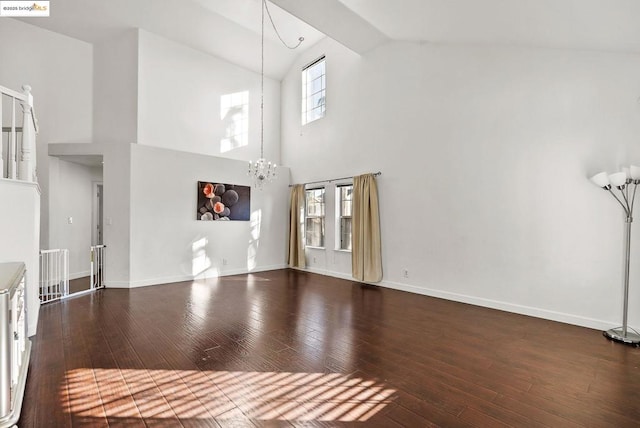 unfurnished living room featuring high vaulted ceiling, dark hardwood / wood-style floors, and a chandelier