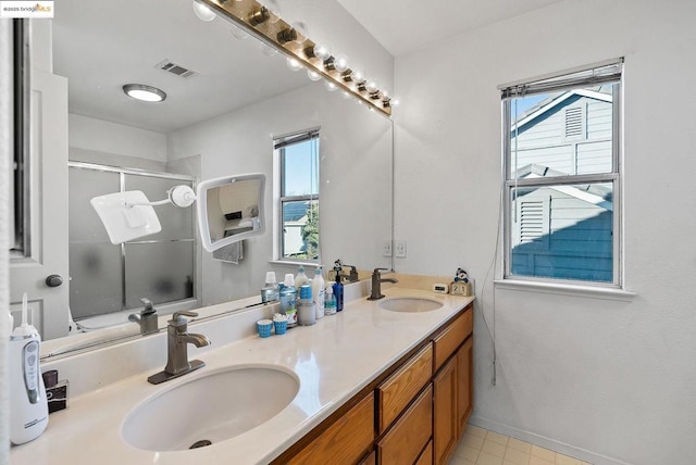 bathroom featuring vanity, a shower with shower door, and a healthy amount of sunlight