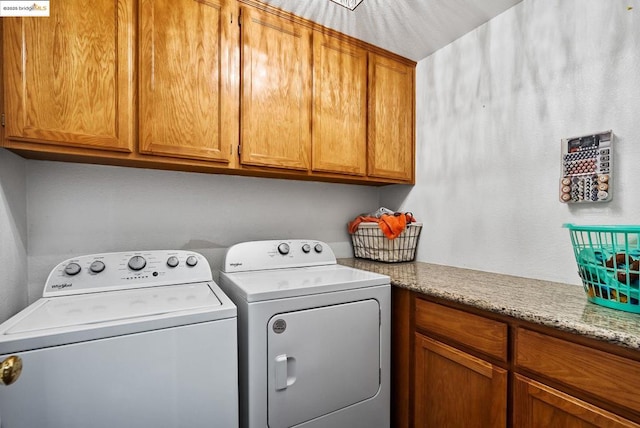 clothes washing area with separate washer and dryer and cabinets