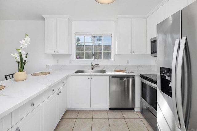 kitchen with sink, white cabinetry, light stone counters, light tile patterned floors, and stainless steel appliances