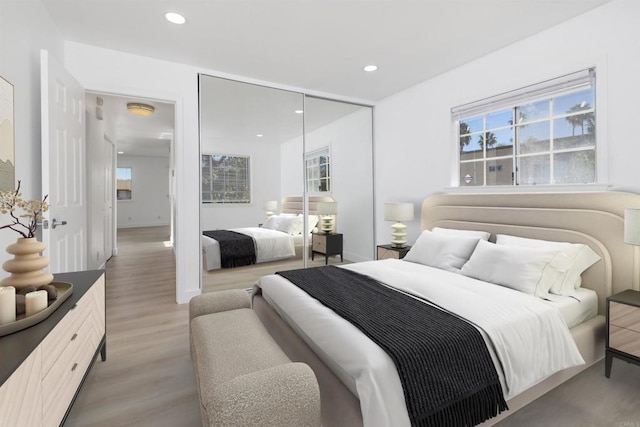 bedroom with multiple windows, hardwood / wood-style floors, and a closet