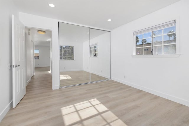 unfurnished bedroom featuring multiple windows, a closet, and light wood-type flooring