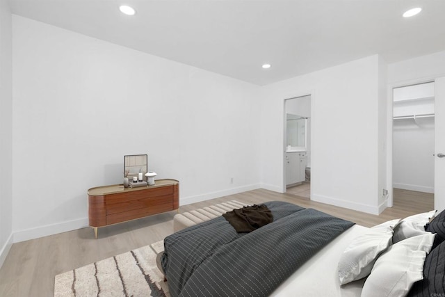 bedroom featuring ensuite bathroom, a spacious closet, a closet, and light hardwood / wood-style flooring