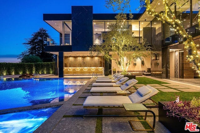 pool at dusk featuring a patio