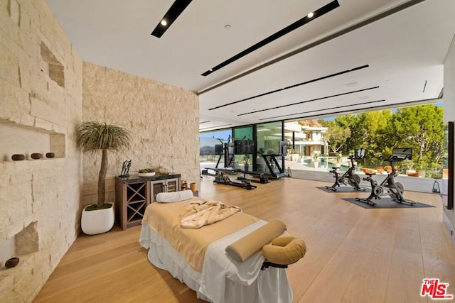 workout area with a wall of windows and light hardwood / wood-style floors