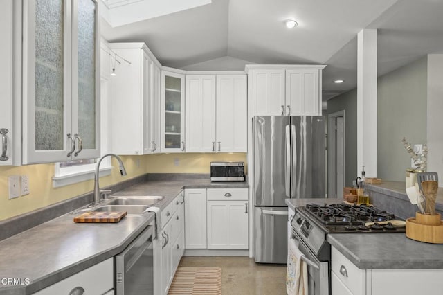 kitchen with sink, stainless steel appliances, white cabinetry, and vaulted ceiling