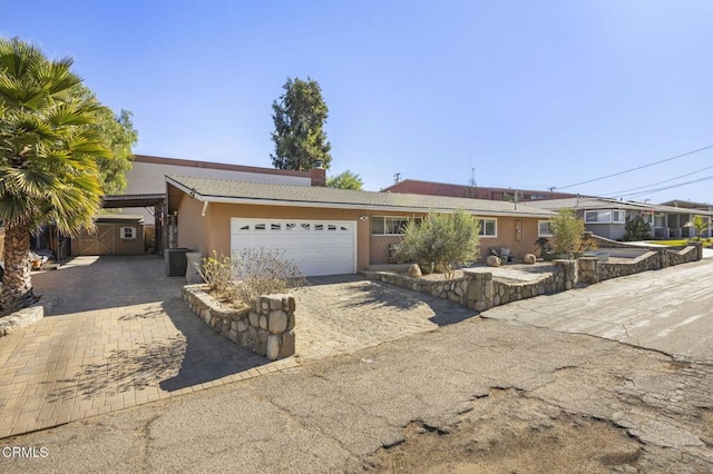 ranch-style home with a garage and central AC unit