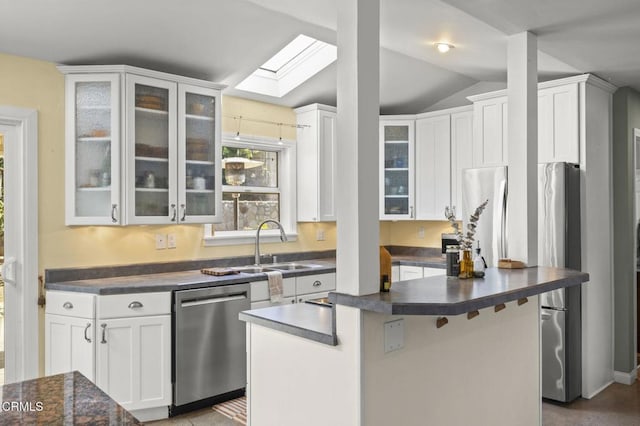 kitchen featuring vaulted ceiling with skylight, white cabinetry, dishwasher, and a kitchen island