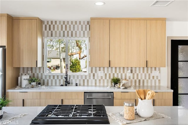 kitchen with light brown cabinetry, dishwasher, sink, decorative backsplash, and gas stovetop