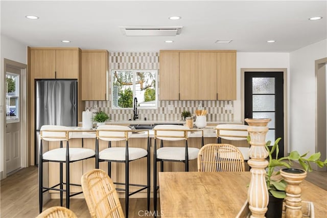 kitchen featuring tasteful backsplash, a kitchen island, stainless steel fridge, and light wood-type flooring