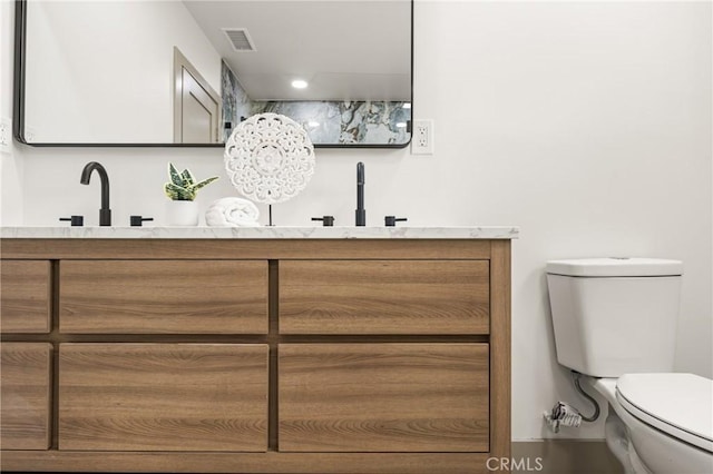 full bath featuring toilet, double vanity, visible vents, and a sink