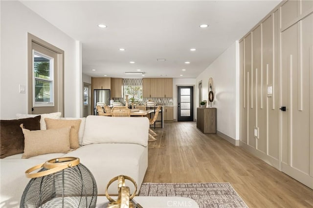 living area with baseboards, recessed lighting, and light wood-style floors