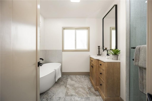 bathroom featuring marble finish floor, walk in shower, a freestanding bath, and vanity