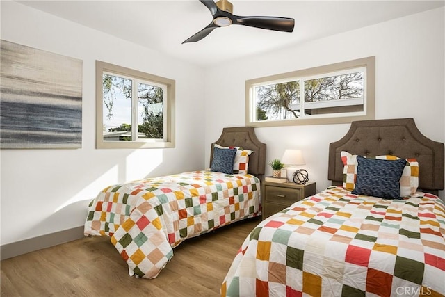 bedroom featuring multiple windows, a ceiling fan, and wood finished floors